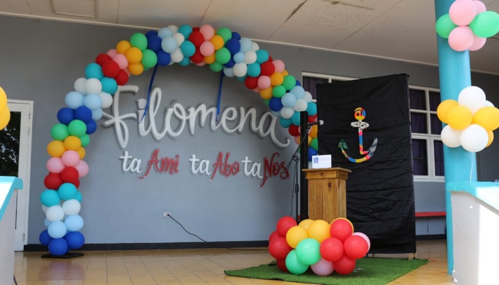 Decorated stage at Filomena Mavo College with colorful balloon arch and an anchor symbol, prepared for a school celebration or ceremony.