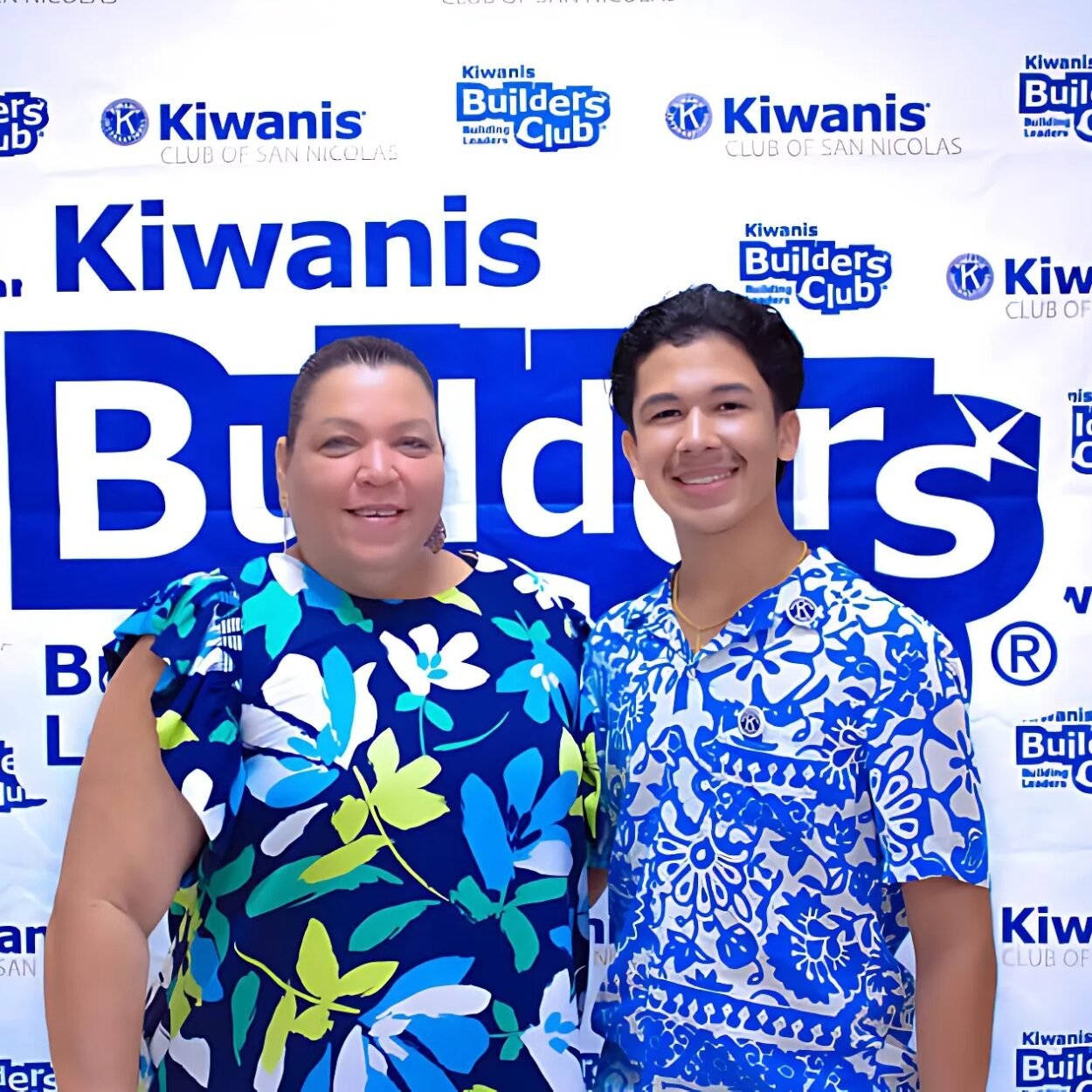 Dean of Filomena College with a student at a Kiwanis Builders Club event, both wearing matching floral-patterned shirts.